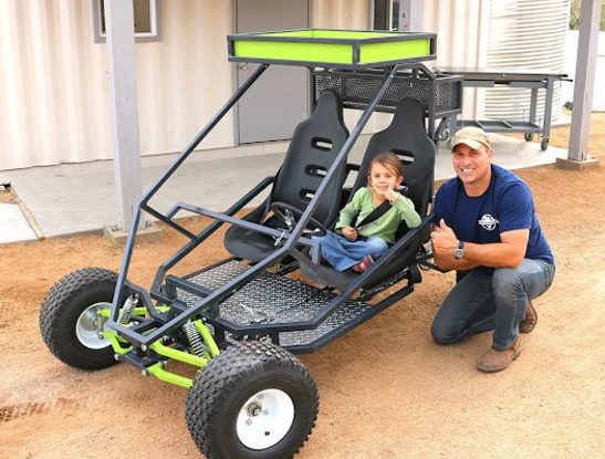 The homesteadonomics builder and a young rider with their finished GrandDaddy buggy